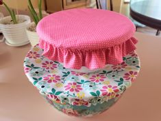 three pillows stacked on top of each other in front of a table with flowers and potted plants