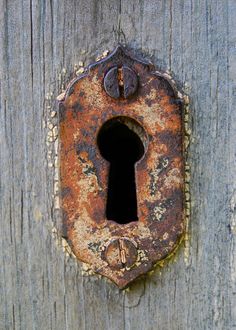 an old rusty keyhole on the side of a wooden door