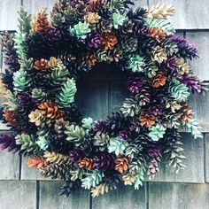 a wreath is hanging on the side of a wooden building with purple and green leaves