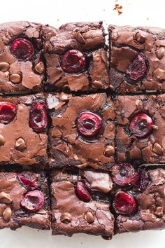 brownies with cherries cut into squares on a white surface, ready to be eaten