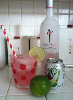 a bottle of booze next to a glass with a lime and a can of soda