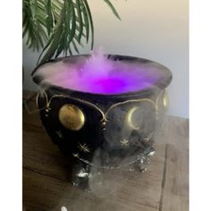 a black bowl with purple light inside on a table next to a potted plant