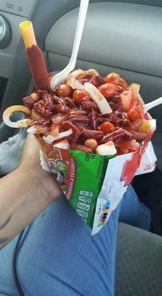 a person is holding up a bag of food in their hand while sitting in the car