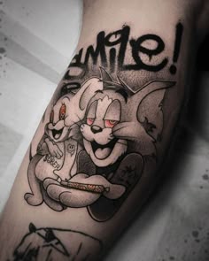 an arm with some tattoos on it that says smile and two cats holding each other