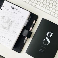 a black and white planner next to a keyboard