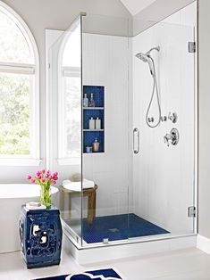 a blue and white bathroom with a shower, sink, toilet and rug in it