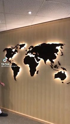 a man standing in front of a wall with a world map on it's side