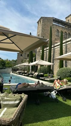 people are lounging on the grass near an outdoor pool