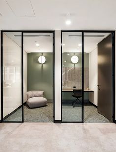 an office with glass walls and doors leading to the other room, including a couch