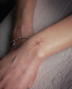 a woman's arm with a small star tattoo on the left side of her wrist