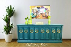 a blue cabinet with two vases and a painting on the wall in the background