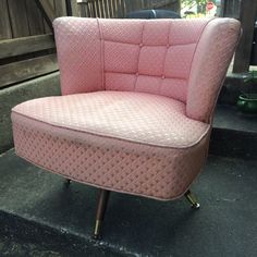 a pink chair sitting on top of a cement floor next to a wooden fence and steps