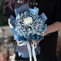 a woman holding a bouquet of blue and white flowers