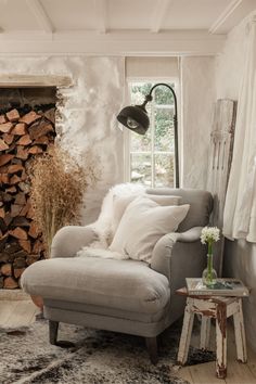 a living room with a couch, chair and firewood stacked on the fireplace mantel