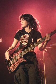 a woman with long hair playing a bass guitar