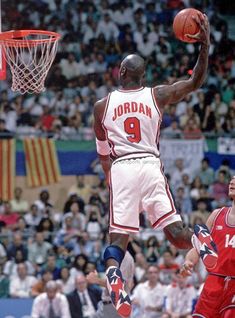 a basketball player jumping up to dunk the ball in front of an audience at a sporting event