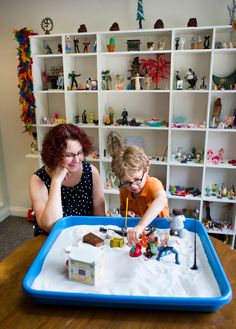 two women sitting at a table playing with toys