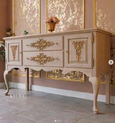 an old dresser with gold paint on the doors and drawers is shown in this room