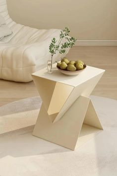 a bowl of fruit sitting on top of a white table next to a bed in a room