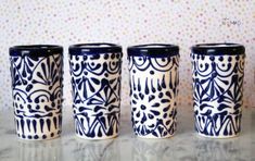 four blue and white cups sitting on top of a counter