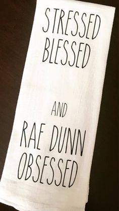 a white towel with black lettering on it that says, stressed and rae dunn obesed