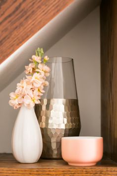 some vases are sitting on a shelf with flowers in the corner next to them