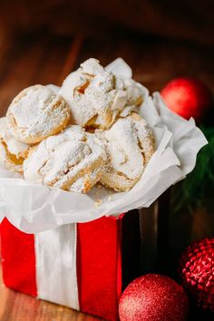 a red box filled with powdered sugar covered cookies