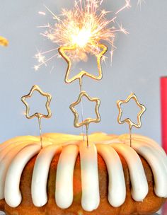 a bundt cake with white icing and stars on top is lit by a sparkler