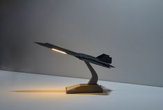 a model airplane on a stand with light coming from it