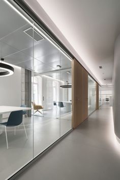 an office with glass walls and white furniture