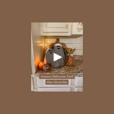 two stuffed animals sitting on top of a kitchen counter next to candles and pumpkins