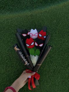 a person is holding some baseball bats on the grass and it's decorated with spiderman faces