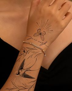 a woman's arm with a bird and flower tattoo on the left side of her arm