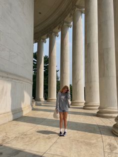 a woman is standing in front of some pillars