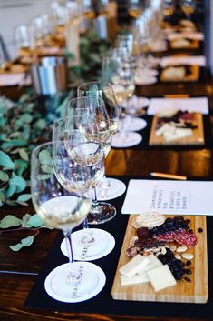 a long table with wine glasses and cheeses on it