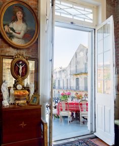 an open door leading to a dining room with paintings on the wall and a table in front of it