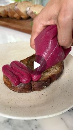 a person is spreading red sauce on a piece of bread