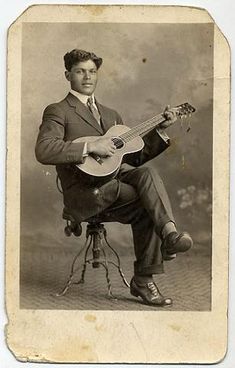 an old black and white photo of a man with a guitar