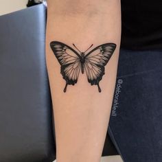 a black and white butterfly tattoo on the arm