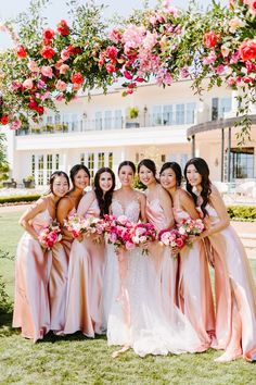 a group of women standing next to each other in front of a flower covered arch