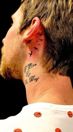 the back of a man's neck with birds on it and an inscription behind his ear