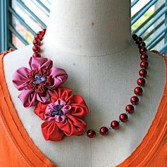 a necklace with flowers and beads on a mannequin