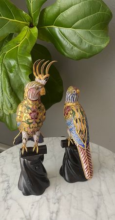 two decorative birds sitting on top of a table