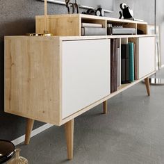 a white and wood sideboard with books on it next to a wall mounted mirror