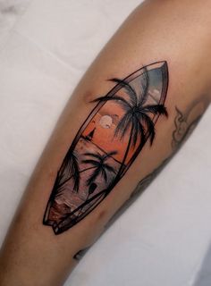 a man's arm with a surfboard and palm trees tattoo on the forearm