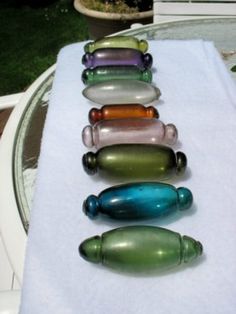 seven glass bottles lined up in a row on a white towel next to a potted plant