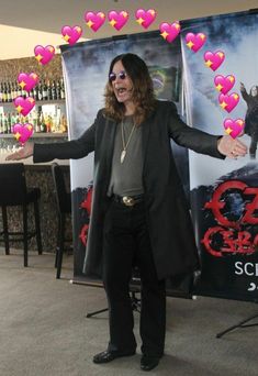 a man standing in front of a poster with hearts coming out of his jacket and sunglasses