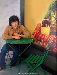 a man sitting at a green table in front of a painting