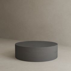 a round concrete table sitting on top of a white floor next to a gray wall