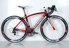 a red and black bike is shown against a white wall with reflective reflection on the floor